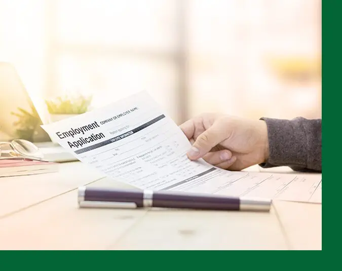 A person holding an employment application on top of a table.